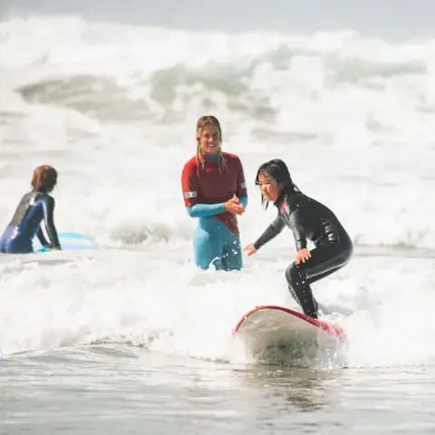Coach et élève dans les vagues, planche rouge