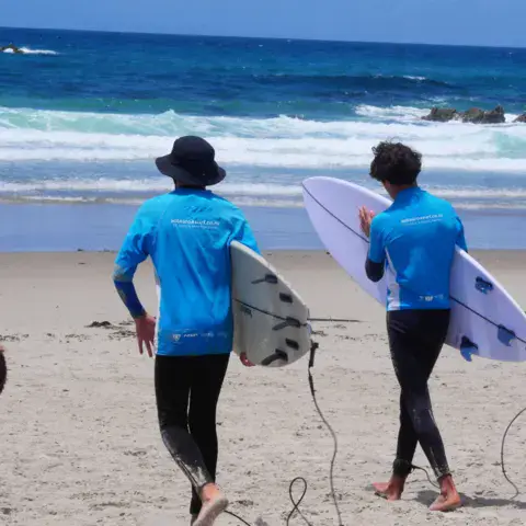 Groupe de surfeurs portant leur planche vers l'eau