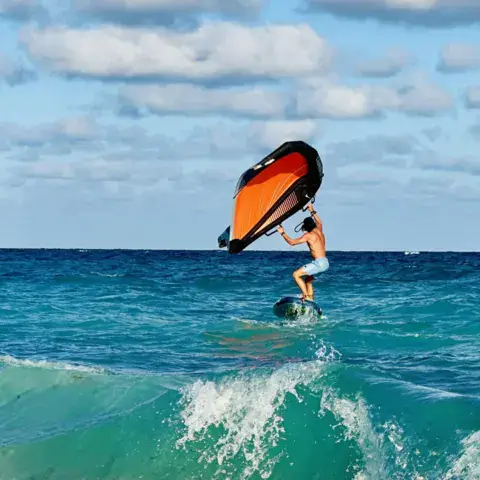 Rider de wing foil dans les vagues devant la plage