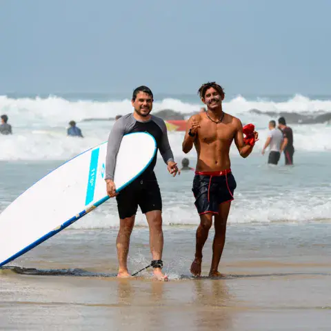 Deux surfeurs avec une planche sur la plage