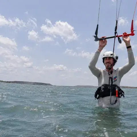 Élève en harnais dans l'eau avec un kite d'entraînement