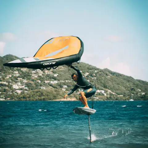Rider en wingfoil près d'une côte boisée