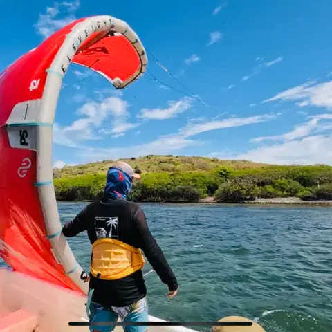 Élève de dos avec une aile de kite près d'un îlet
