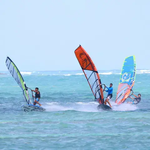 Trois planchistes au large de la plage
