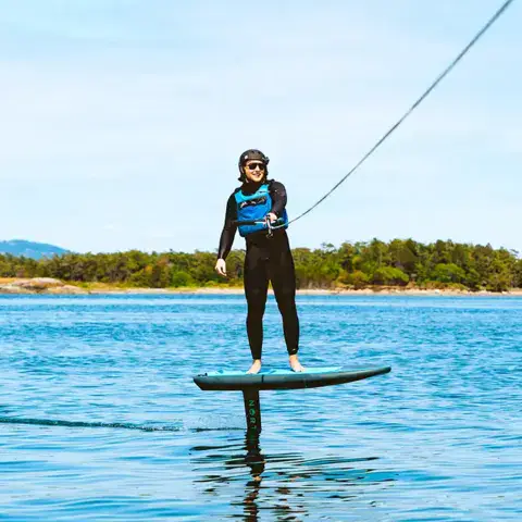 Élève debout sur un foil près de la côte