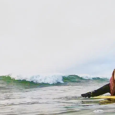 Surfeuse allongée sur sa planche, en attente d'une vague
