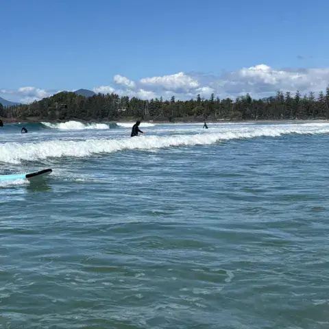 Élève debout sur sa planche dans les vagues