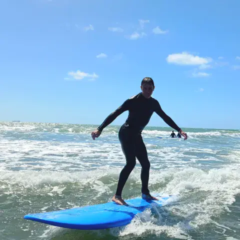 Un élève debout sur une planche en mousse dans les vagues