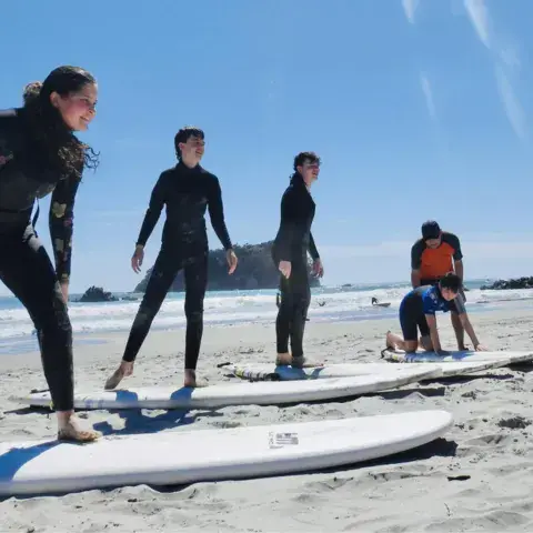 Moniteur montrant le lever sur planche à un petit groupe, sur le sable