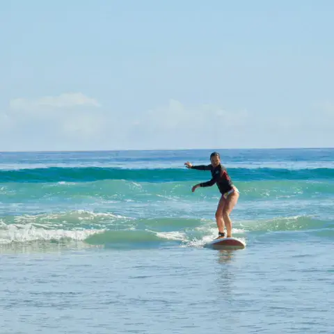 Surfeuse debout sur sa planche, mer calme