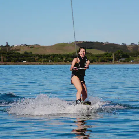 Jeune femme sur un wakeboard, tirée sur l'eau calme