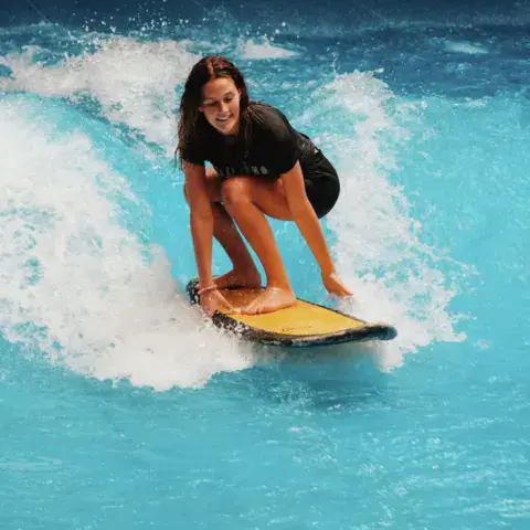 Surfeuse accroupie sur la vague