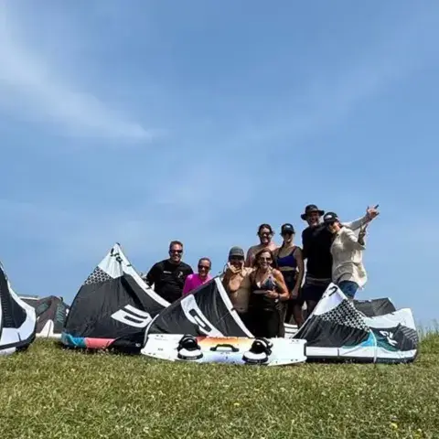 Groupe de kitesurfeurs derrière leurs ailes sur l'herbe
