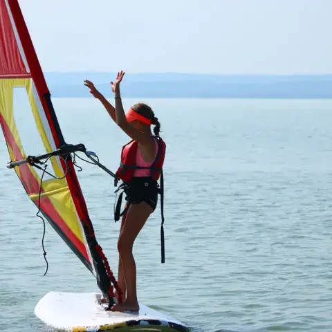 Élève de windsurf sur le lac avec une voile jaune et rouge