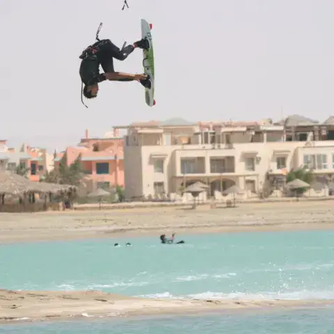 Kitesurfeur en saut devant la lagune et les bâtiments