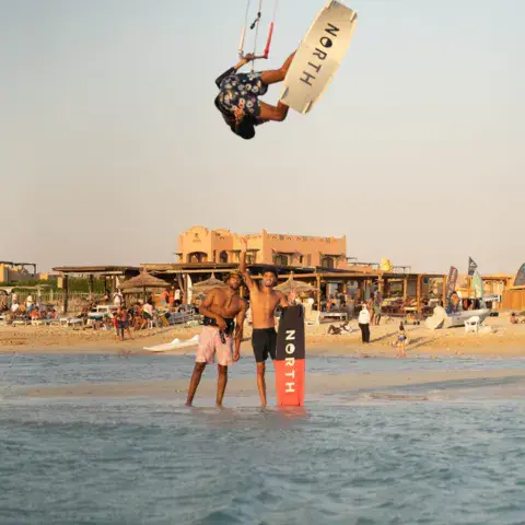 Kitesurfeur en saut devant la plage et ses bâtiments