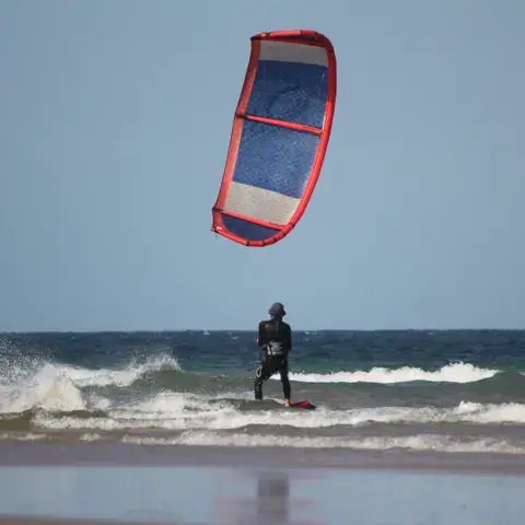 Kitesurfeur sur la vague, kite rouge et bleu