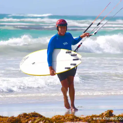Kitesurfeuse sortant de l'eau avec sa planche