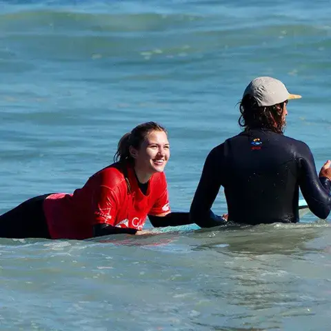 Moniteur et élève couchés sur la planche dans l'eau