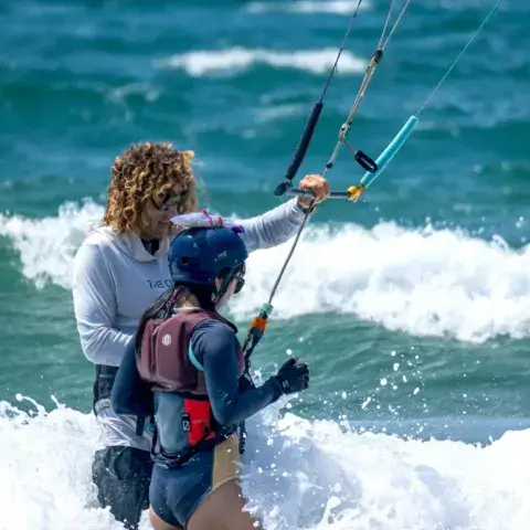 Moniteur accompagnant un élève dans les vagues