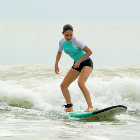 Une élève debout sur sa planche dans les vagues