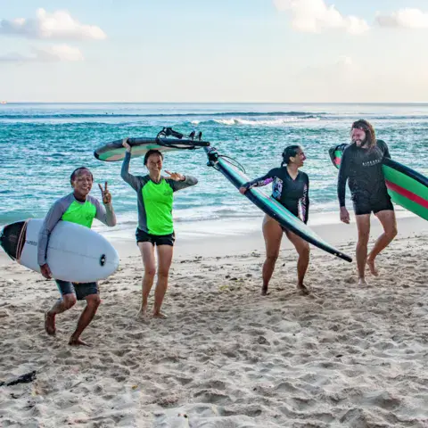 Un groupe d'élèves sur la plage avec leurs planches