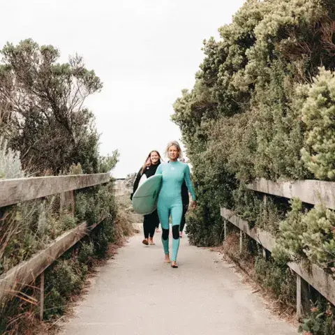 Deux surfeuses avec leurs planches sur le chemin de la plage