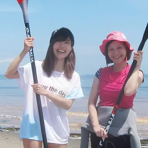 Deux élèves avec leurs pagaies sur la plage
