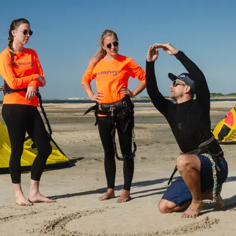 Un moniteur explique les bases à deux élèves sur la plage
