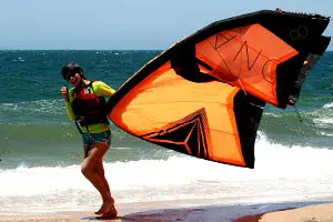 Kitesurfeuse portant son aile sur la plage