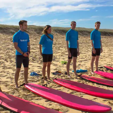 Moniteurs alignés sur la plage devant les planches en mousse