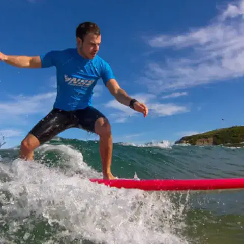 Moniteur surfant une vague sur une planche rouge