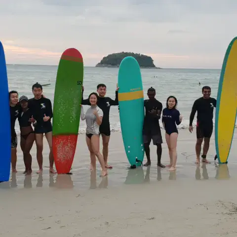 Groupe d'élèves avec leurs planches sur la plage