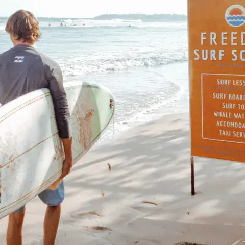 Surfeur avec sa planche près du panneau de l'école