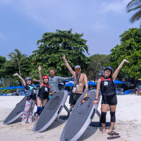 Groupe d'élèves avec leurs planches sur la plage