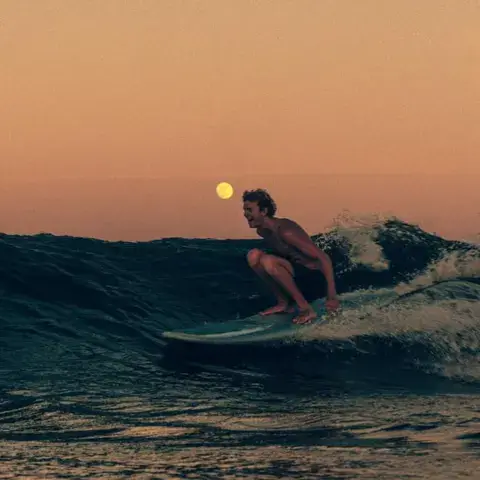 Surfeur sur une vague au coucher du soleil