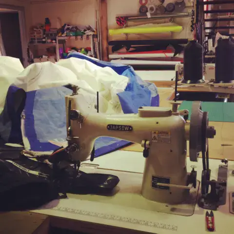Machine à coudre industrielle et voiles en cours de réparation
