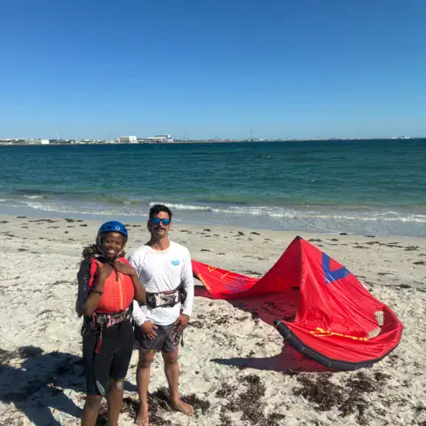Moniteur et élève avec un kite déployé sur le sable