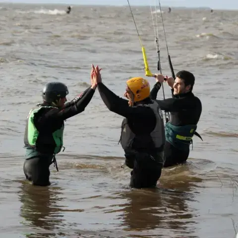 Instructeur et élèves dans l'eau du fleuve pendant un cours de kitesurf