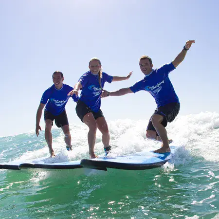 Trois personnes debout sur leurs planches dans une vague