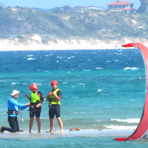 Moniteur et élèves dans l'eau avec un kite rouge