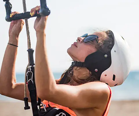Élève casqué apprenant à piloter une aile de kitesurf