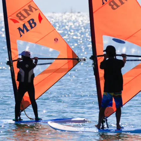 Deux élèves en cours de windsurf sur une mer calme
