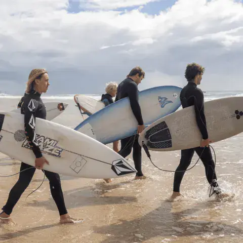 Surfeurs portant leurs planches sur la plage