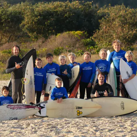 Groupe de surfeurs avec leurs planches sur la plage