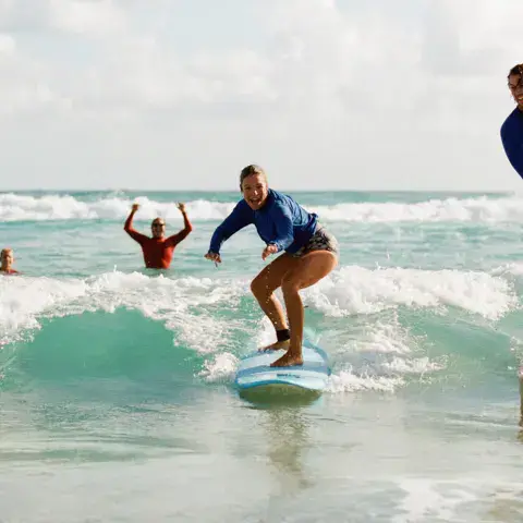 Élèves debout sur leurs planches dans les vagues