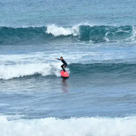 Surfeur sur une planche rouge dans une vague