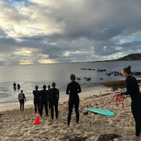 Moniteurs et élèves en combinaison sur la plage avant la séance