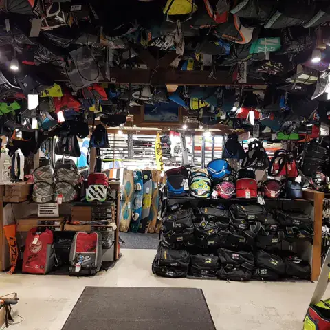Sacs et équipements de kitesurf rangés au plafond et au sol de la boutique