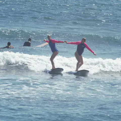 Deux élèves debout sur leurs planches dans les vagues